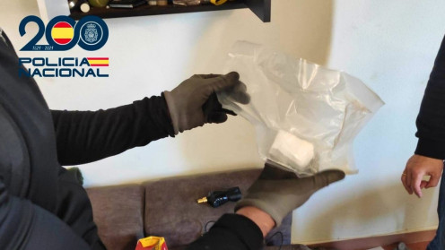 Un despliegue de agentes de la Policía Nacional frente a un portal, con material incautado como bolsas de sustancias blancas y plantas de marihuana.