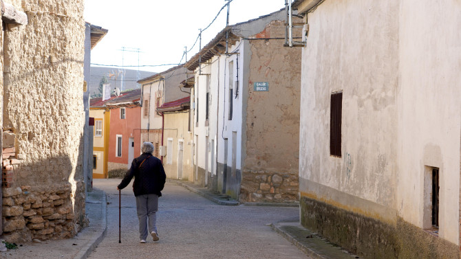 ICAL. Imagen de archivo de una mujer de avanzada edad camina por un pueblo de Valladolid